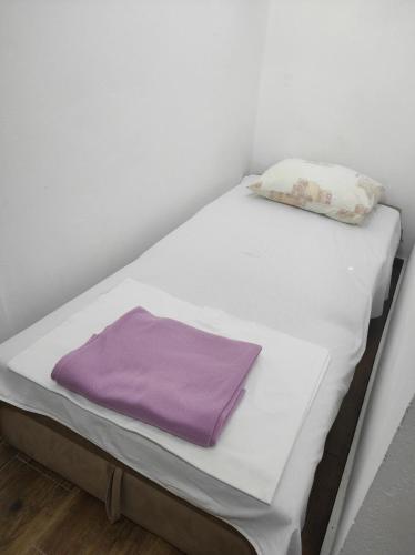 a small bed with a purple blanket on it at Rustic Stone House in Bar