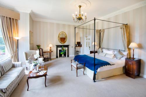 a bedroom with a canopy bed and a living room at Taplow House Hotel & Spa in Maidenhead