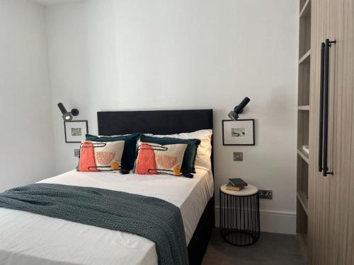 ロンドンにあるBrand new 3-bedroom home in Londonのベッドルーム1室(オレンジと緑の枕が付いたベッド1台付)