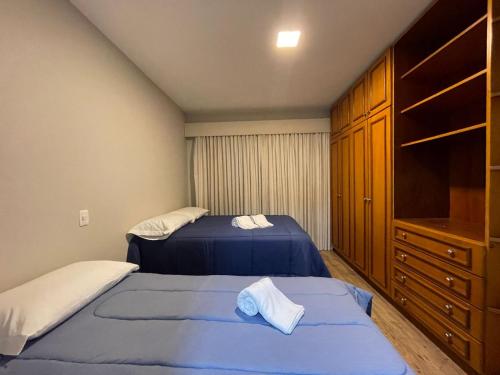 two beds in a small bedroom with a dresser at Apartamento a 100m da Rua Coberta in Gramado