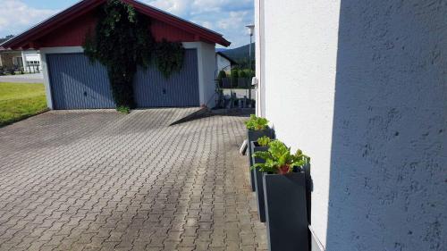 a brick driveway with two potted plants next to a building at Urlaub am Sonnenhügl in Rinchnach