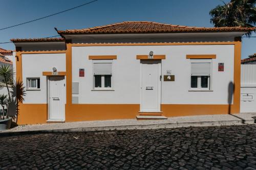 Casa blanca y naranja con dos puertas en Vila Saudade, en Costa da Caparica