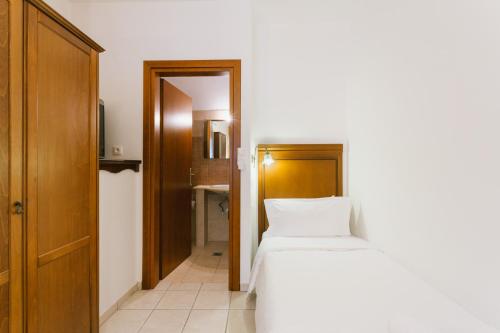 a bedroom with a white bed and a wooden door at Archontiko Anemos in Makrinítsa