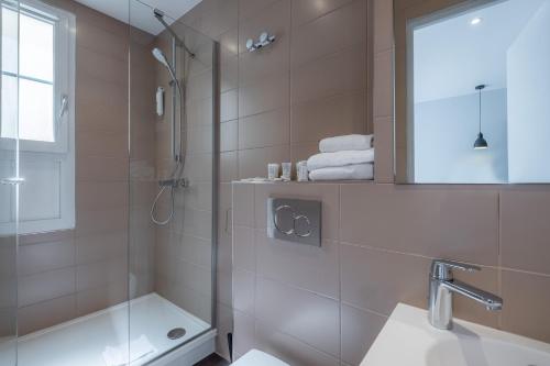 y baño con ducha, bañera y lavamanos. en Hotel Lilas Blanc en París