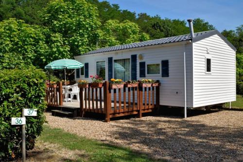 un petit hangar blanc avec une table et un parasol dans l'établissement Camping Onlycamp Le Val Joyeux, à Château-la-Vallière