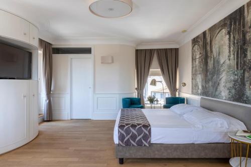 a bedroom with a bed and two blue chairs at Hotel Scalinata Di Spagna in Rome