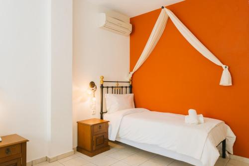 two beds in a bedroom with an orange wall at Archontiko Anemos in Makrinítsa