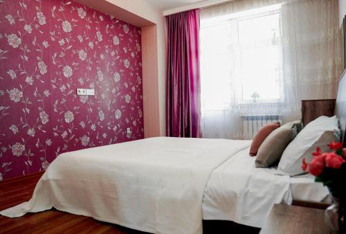 um quarto com uma cama branca e uma parede roxa em Комфортная квартира возле метро em Baku