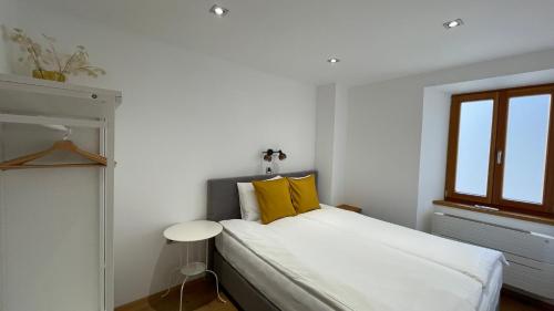 a white bedroom with a bed with yellow pillows at SeaHouse Apartments in Piran