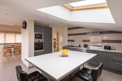 une cuisine avec une table blanche et des armoires noires dans l'établissement La Terrasse de Montcenis, à Montcenis