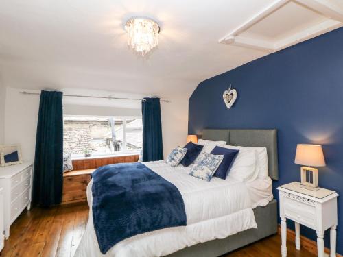 a bedroom with a bed with blue walls and a window at White Swan Cottage in Bakewell