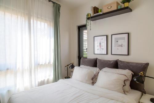 特拉維夫的住宿－The Alexander Apartment，一间卧室配有一张带白色床单的床和一扇窗户。