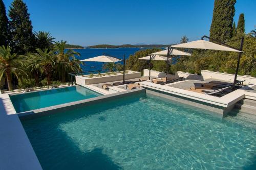 a swimming pool with chairs and umbrellas at Hotel Moeesy, Blue & Green Oasis in Hvar
