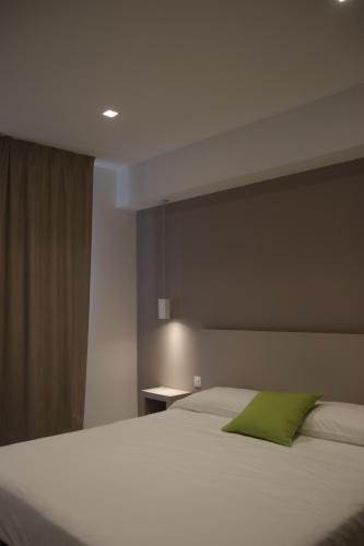 a bedroom with a white bed with a green pillow at SALAPIA SALIS RESORT in Margherita di Savoia