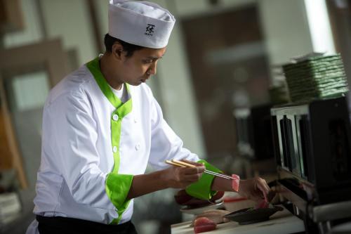 a man in a chefs hat preparing food in a kitchen at Holiday Inn Cikarang Jababeka by IHG in Cikarang