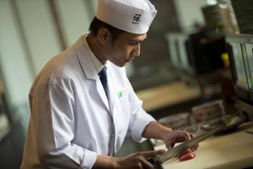 a man in a chefs hat preparing food in a kitchen at Holiday Inn Cikarang Jababeka by IHG in Cikarang