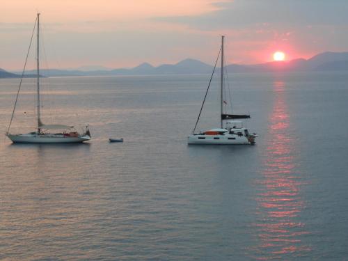 dos veleros en el agua con la puesta de sol en el fondo en HydraVista (Lily) en Hydra