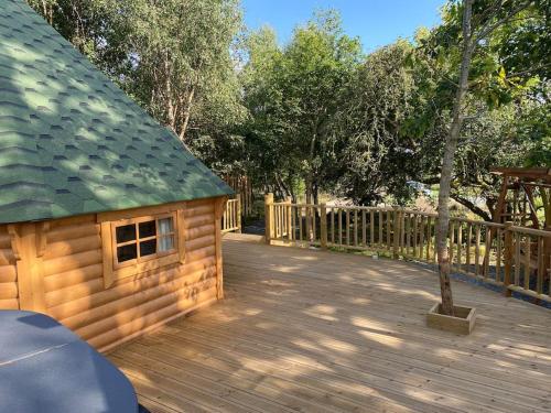 una terraza de madera con una casa pequeña. en Craigshannoch Luxury 1 bed woodland lodge hot tub en Kintore