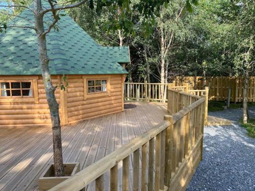 una terraza de madera con una cabaña con techo verde en Craigshannoch Luxury 1 bed woodland lodge hot tub en Kintore