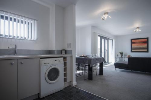 a kitchen with a washing machine and a dining room at Maritime Quarter - 2 Bedroom Apartment - SA1 Beach Front Fishermans Way in Swansea