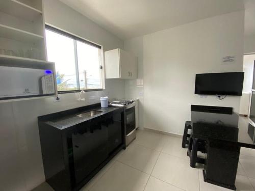 a small kitchen with a sink and a microwave at Condominio Boa Vista in Pontal do Paraná