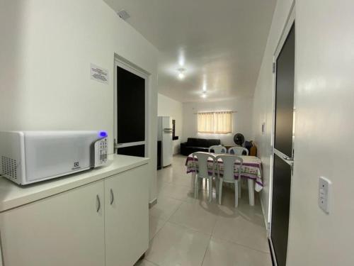 a kitchen with a microwave and a living room at Condominio Boa Vista in Pontal do Paraná