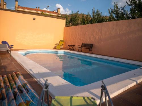 a swimming pool with chairs next to a wall at LA CASA DE ROSA in Teruel