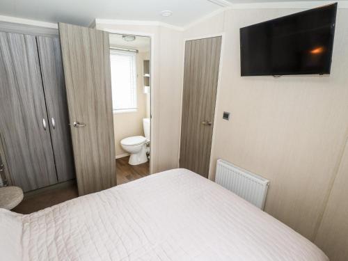 1 dormitorio con 1 cama y TV en la pared en 19 The Brambles, en Humberston