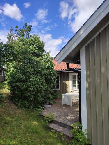 a wooden deck next to a house with a tree at Villa i Norrtälje in Norrtälje