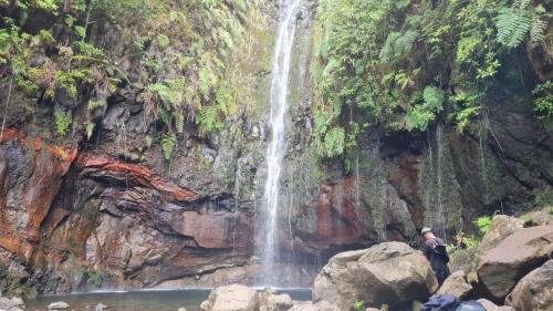 a waterfall with a man standing in front of it at Pensão Fernandes in Porto Moniz