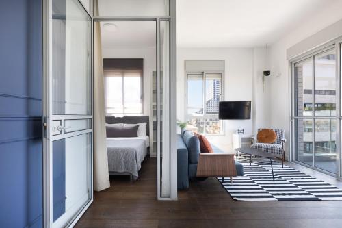 een woonkamer met een bed en een kamer met een bank bij Bauhaus Boutique by TLV2rent in Tel Aviv