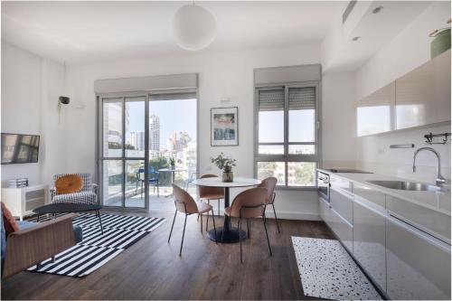 a white kitchen with a table and chairs at Bauhaus Boutique by TLV2rent in Tel Aviv