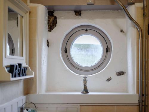 ein Bad mit einem runden Fenster in der Wand in der Unterkunft Peak Cottage in Bakewell