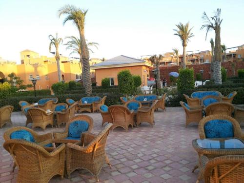 a group of chairs and tables and palm trees at Villa Yasmin404 in Marsa Matruh