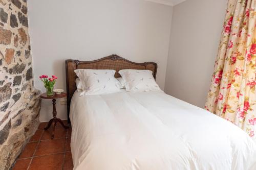 a bed with white sheets and pillows in a bedroom at Casa das Regueiras in Santiago de Compostela
