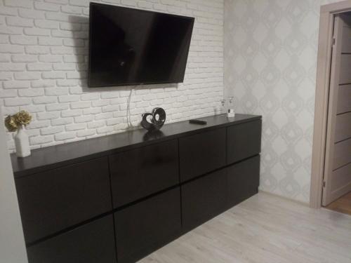 een zwarte dressoir met een flatscreen-tv aan de muur bij Аппартаменты в центре Олайне для комфорта. in Olayne