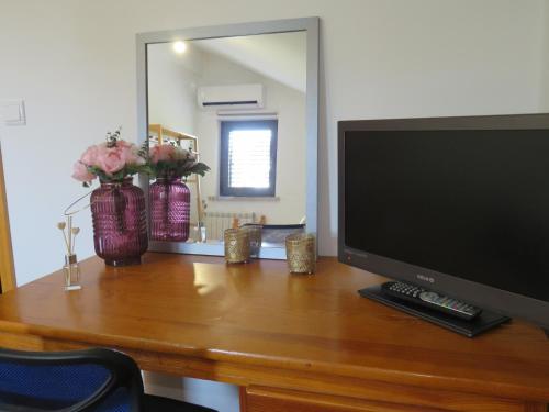 a desk with a television and flowers on it at Cantinho do Mel in Castro Daire