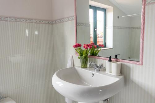 ein Badezimmer mit einem Waschbecken, einem Spiegel und Blumen in der Unterkunft Casa das Regueiras in Santiago de Compostela