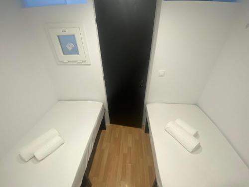 2 camas blancas en una habitación pequeña con puerta negra en Le.Chris Central Dorms en Rethymno Town