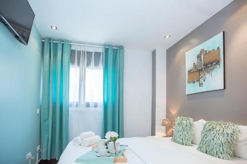 1 dormitorio con cama blanca y cortinas azules en AL36 - Apartamento de lujo a 100 metros de playa, en Lloret de Mar