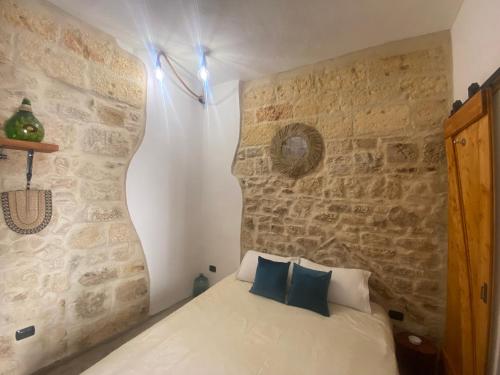 - une chambre avec un lit et un mur en pierre dans l'établissement Dimora PietrAnima, à Bari