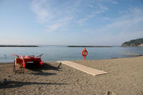 a red boat sitting on a beach next to the water at Case Vacanze Borgo Faraldi in Villa Faraldi