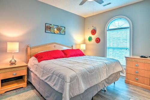 a bedroom with a bed with red pillows and a window at Colorful Myrtle Beach Golf Club Condo with Pool in Myrtle Beach