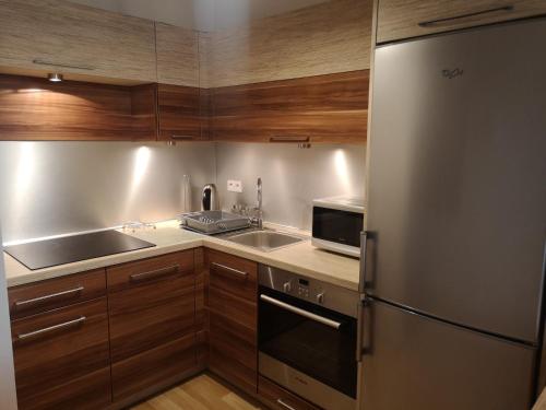 cocina con armarios de madera y nevera de acero inoxidable en Apartament Marzenie 11 - Opole, en Opole