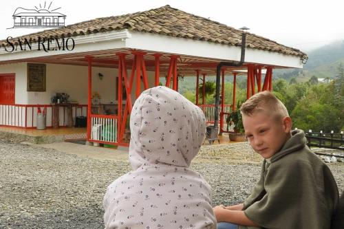 a young boy sitting next to a statue of a person at Hotel Rural SAN REMO in Santa Rosa de Cabal