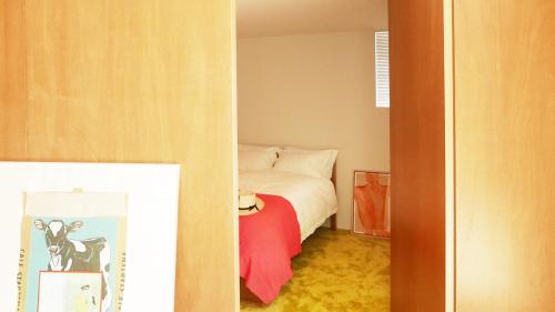 Akizuki OKO art&inn في Asakura: غرفة نوم صغيرة مع سرير وبطانية حمراء