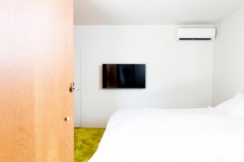 a bedroom with a bed and a tv on the wall at Akizuki OKO art&inn in Asakura