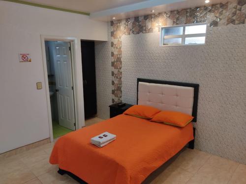 a bedroom with a bed with an orange blanket at Aparta-Hotel El Dorado in Aguadas