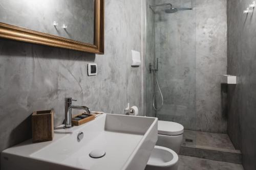 a bathroom with a sink and a toilet and a mirror at Casa di Melo - Organic Country Hotel in Cassibile