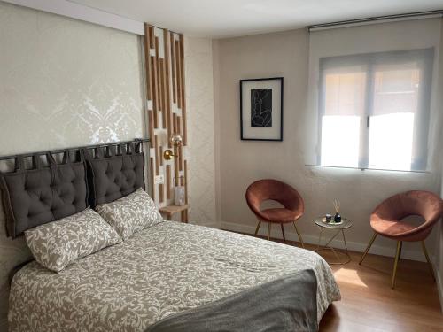 a bedroom with a bed with two chairs and a window at Precioso apartamento muy cerca de Méndez Alvaro in Madrid